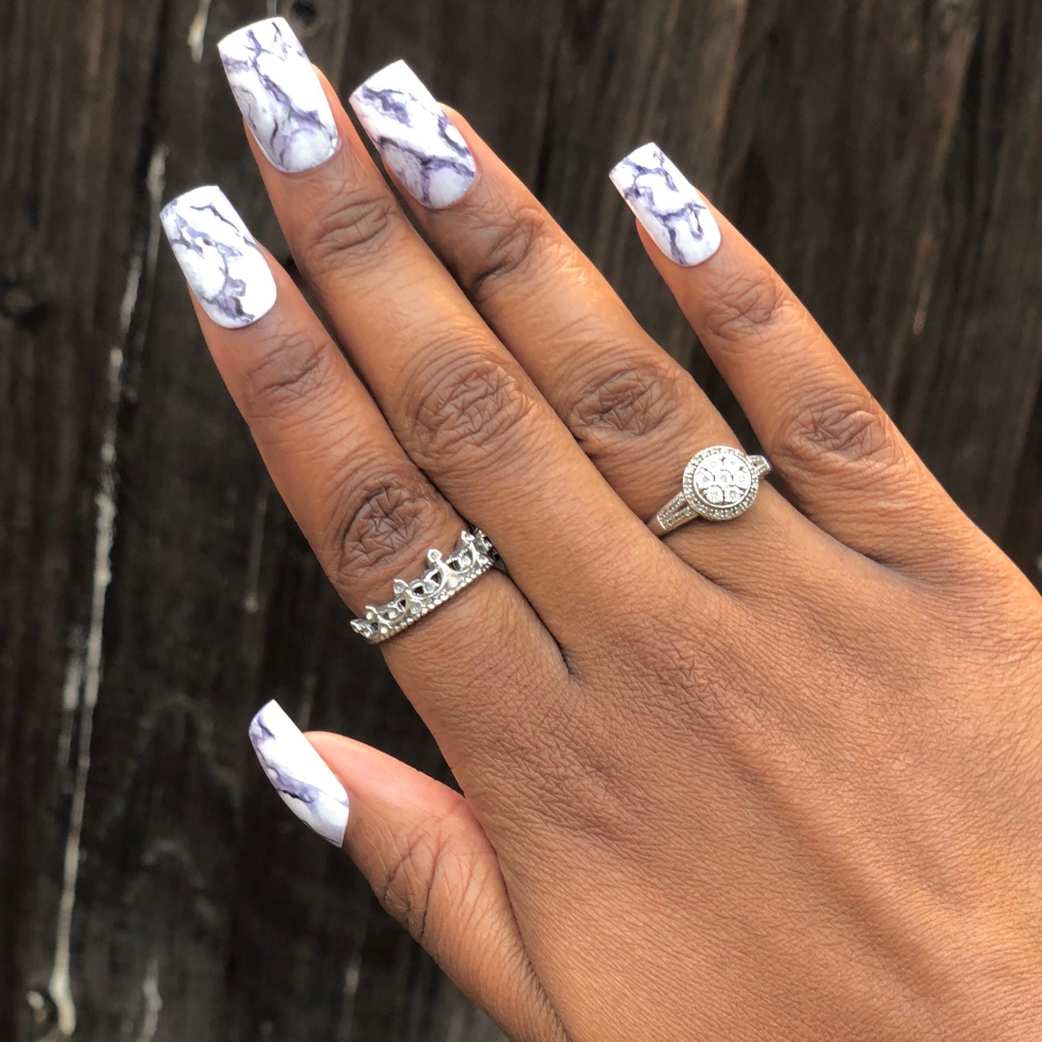 Manicure hand wearing marble press on nails.