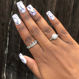 Manicure hand wearing marble press on nails.