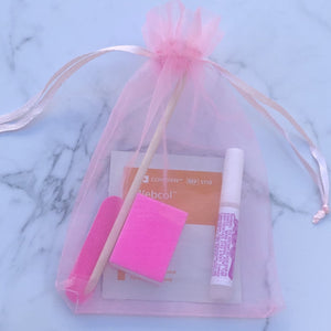 Press on nail application kit in pink bag with nail glue, nail file, nail buffer, alcohol wipe and cuticle pusher.