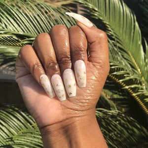 Manicure hand wearing gold foil milk bath press on nails.