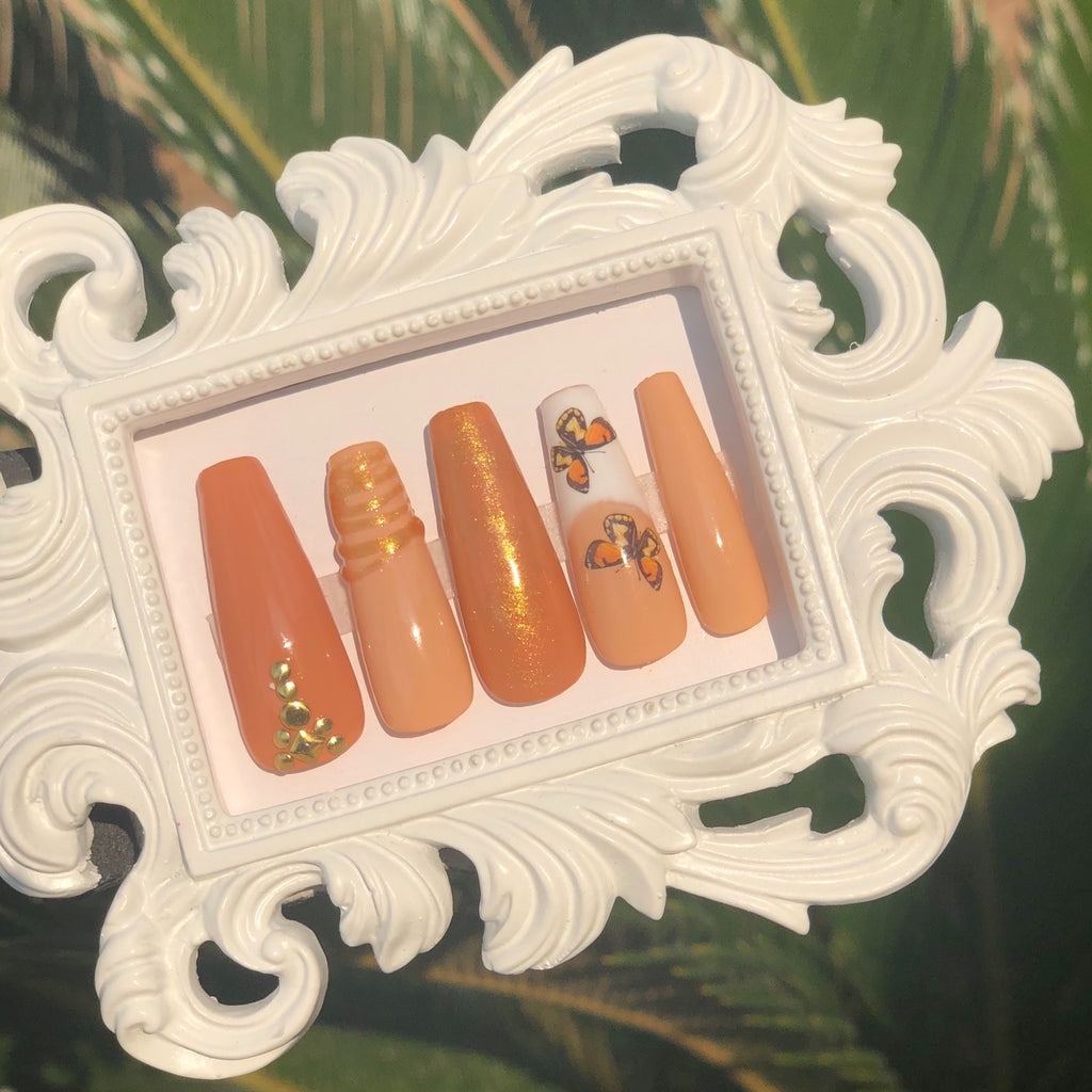 Fall press on nails with brown and orange colors, gold gems and French tip butterflies.