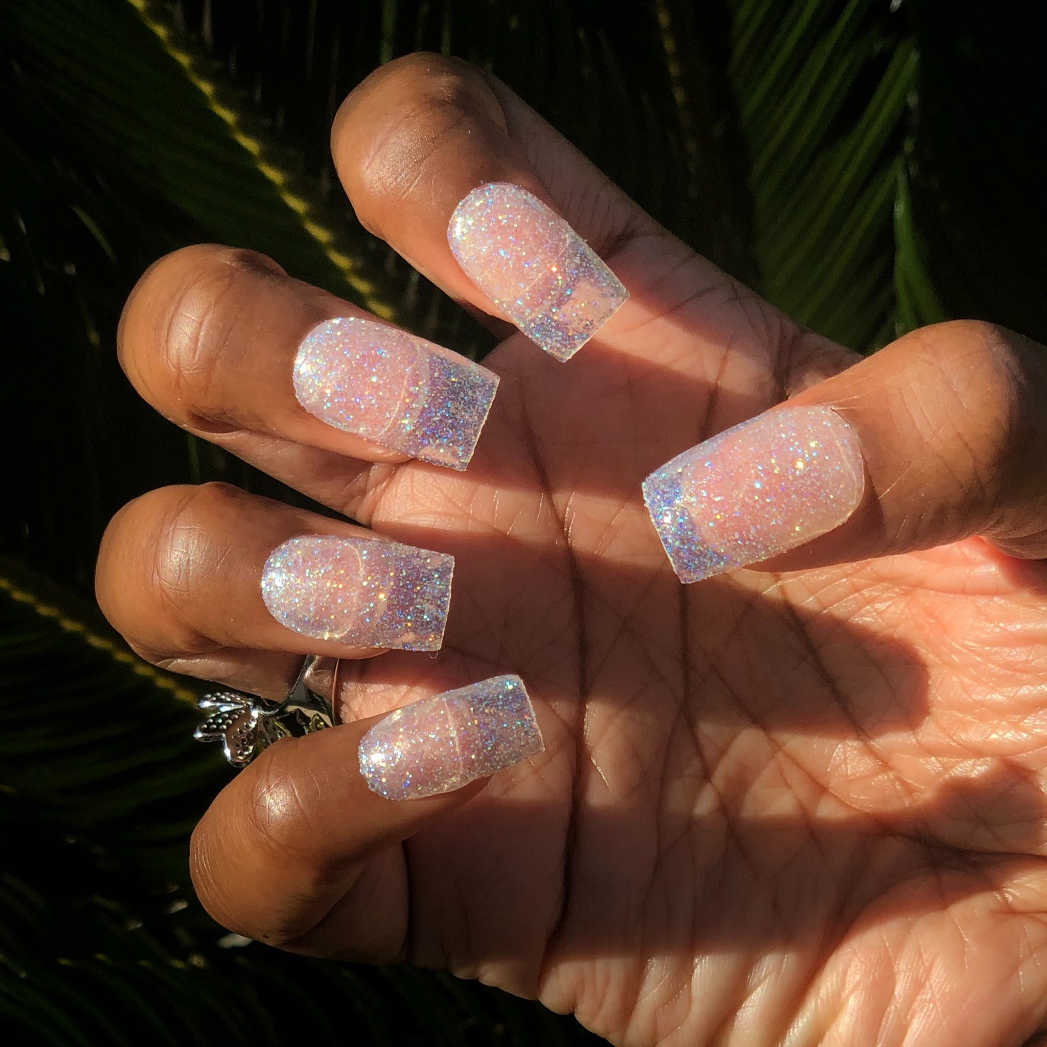 Manicure hand wearing clear glitter press on nails.